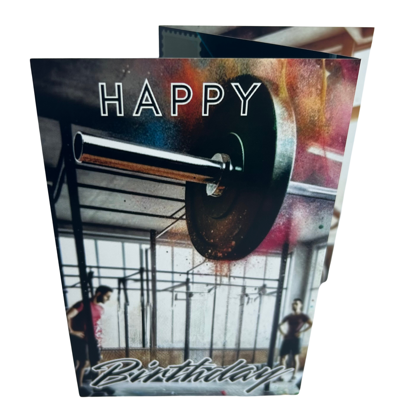 Trifold Male Gym Birthday Card from the Push the Limit Range. Image shows the folded card depicting front with a background of a gym and the end of a large heavy barbell emerging from the right. The caption reads 'Happy Birthday'.