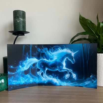 Blue unicorn artwork on a dark background with a candle and plant in the background