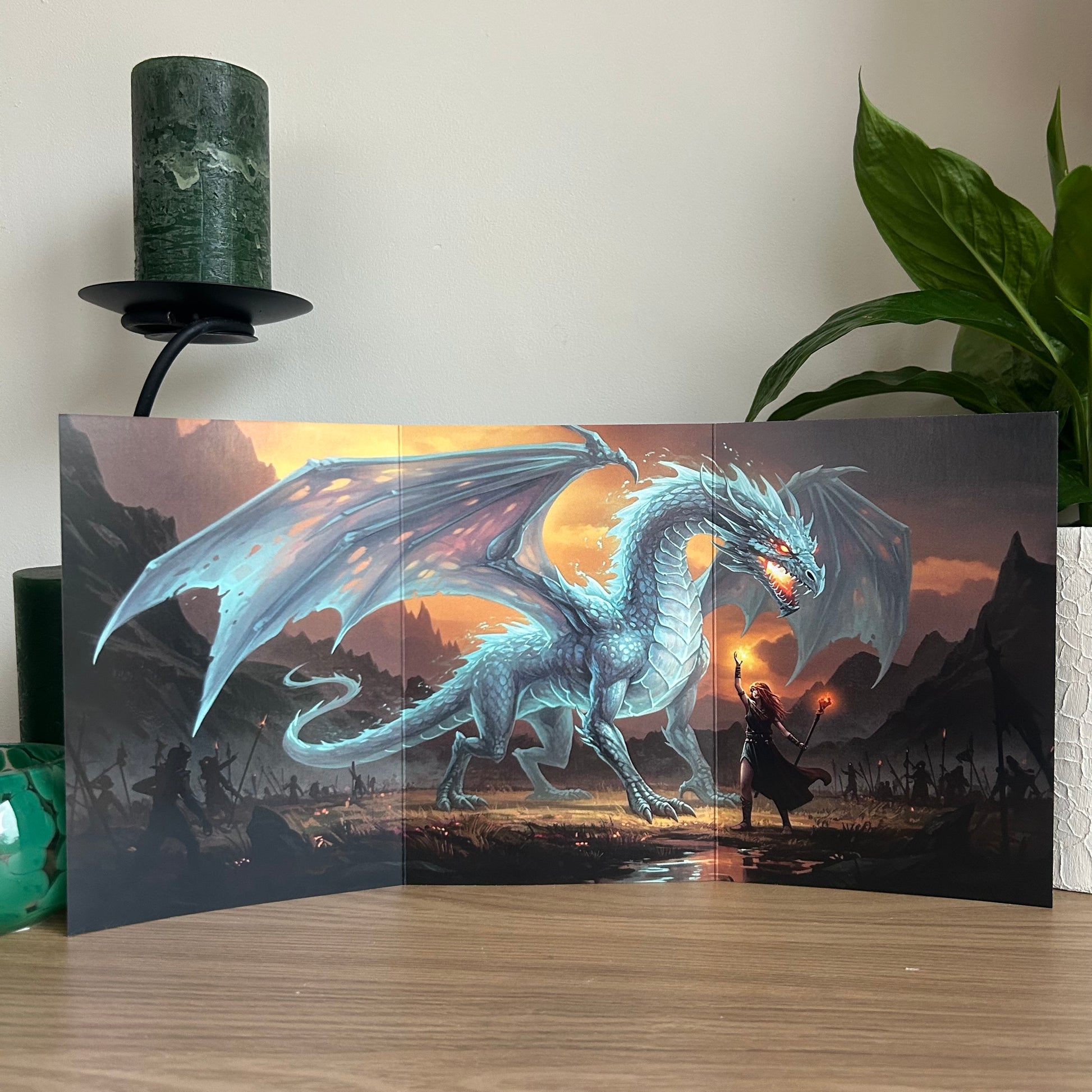 Framed artwork of a dragon and warrior on a wooden surface with a plant in the background