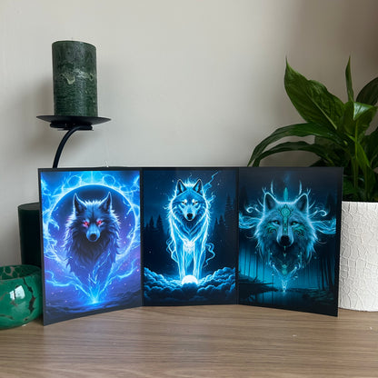 Wolf-themed triptych greetings card on a wooden surface with a plant and candle in the background.