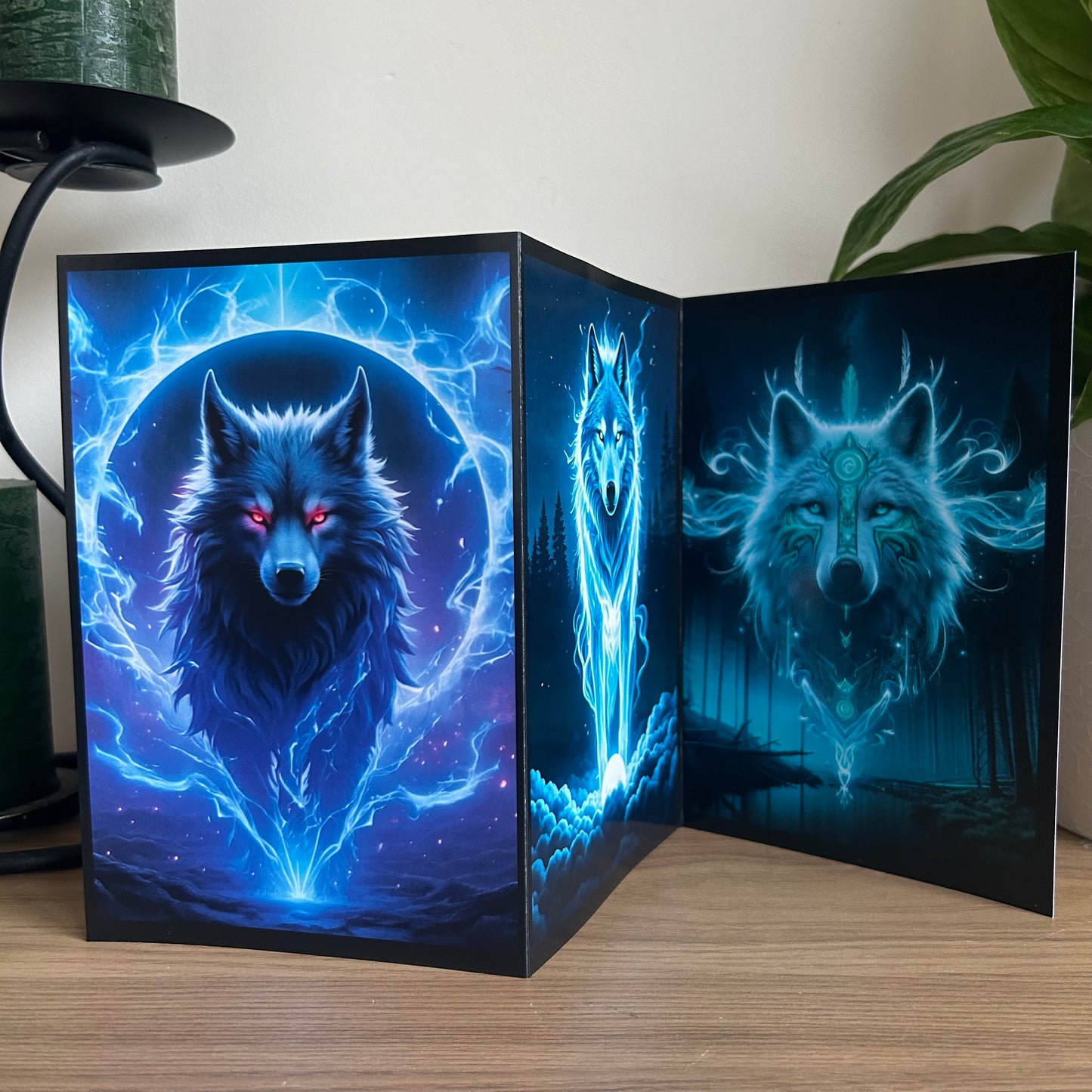 Glowing wolf-themed triptych greetings card with blue and purple lighting on a wooden surface.