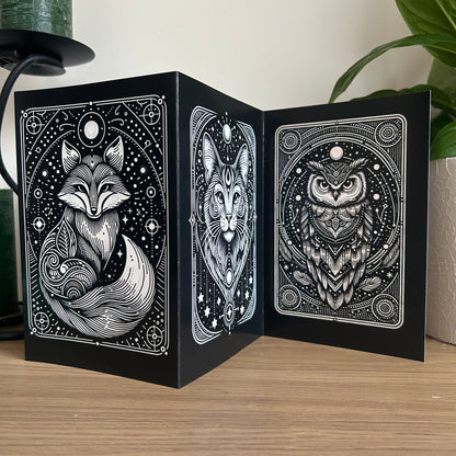 Black card box with fox, cat, and owl illustrations on a wooden surface.