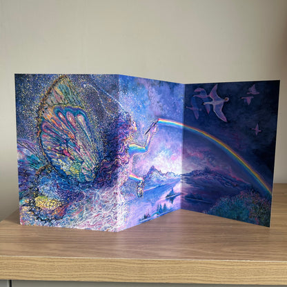 Trifold self-sealing Greeting card with a fairy and rainbow design on a wooden surface