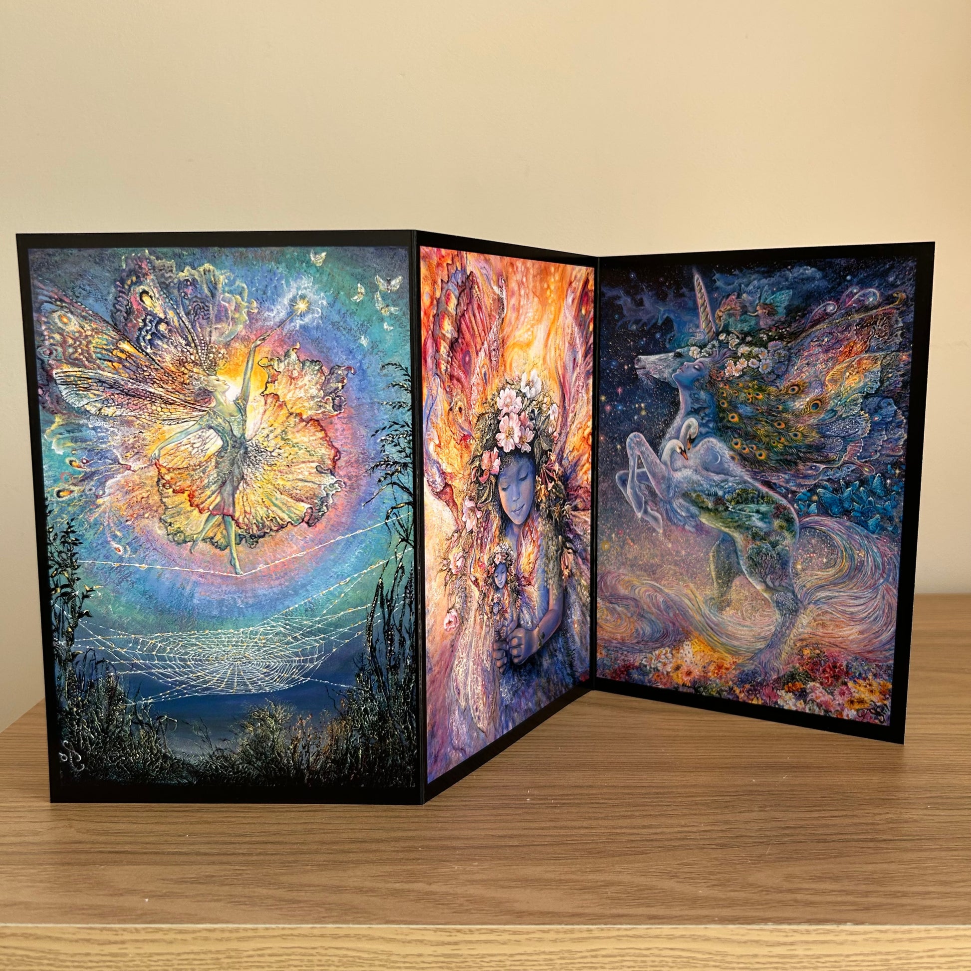 Three-panel self-sealing greetings card UK with artistic designs of a unicorn and fairy figures on a wooden surface.