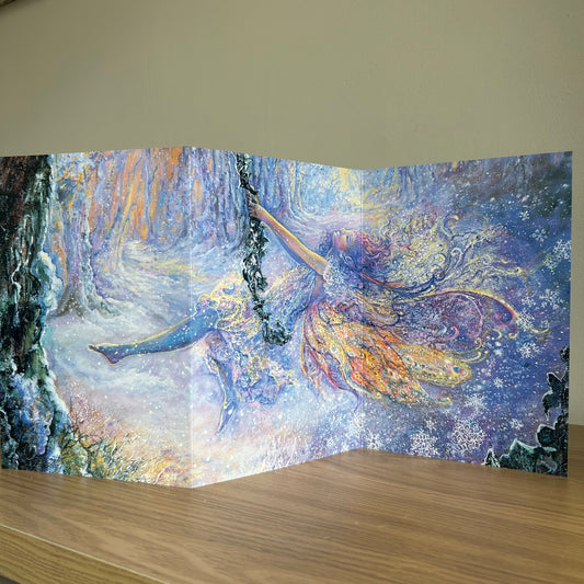 Trifold self-sealing greetings card featuring Fairy tale scene with a fairy swinging in the snow in a forest displayed on a shelf