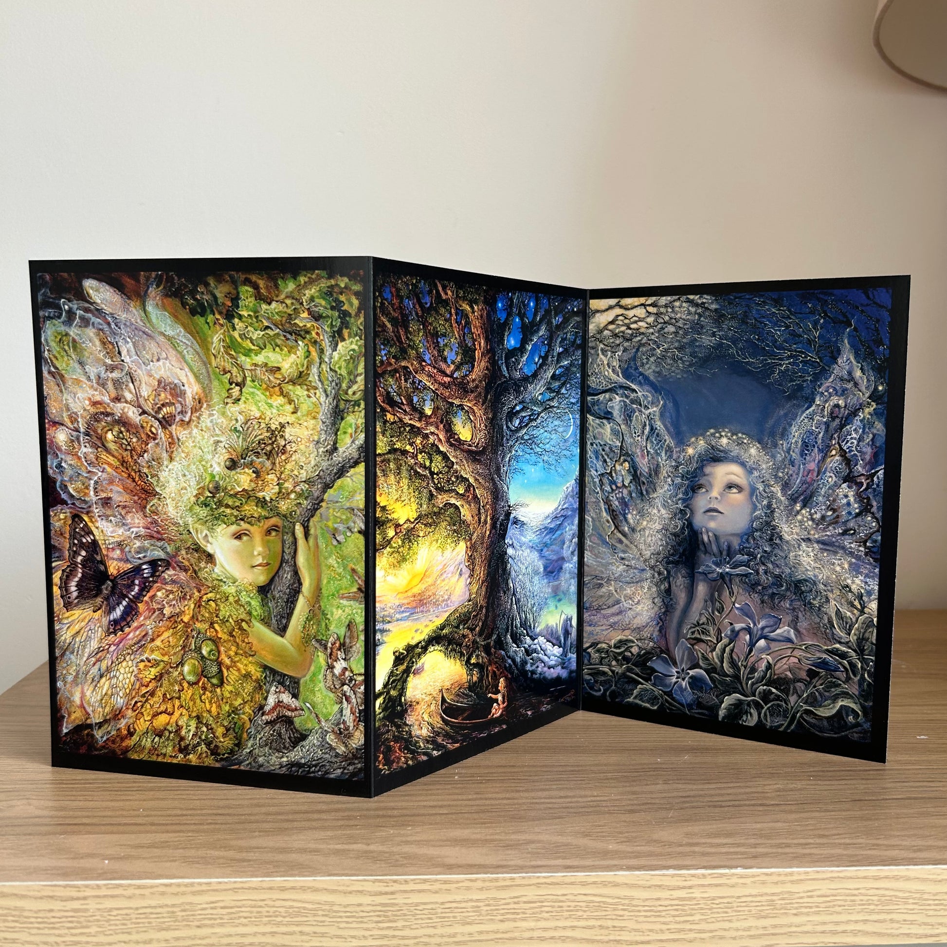 Three-panel self-sealing greetings card with artistic designs of nature and fairy figures on a wooden surface.