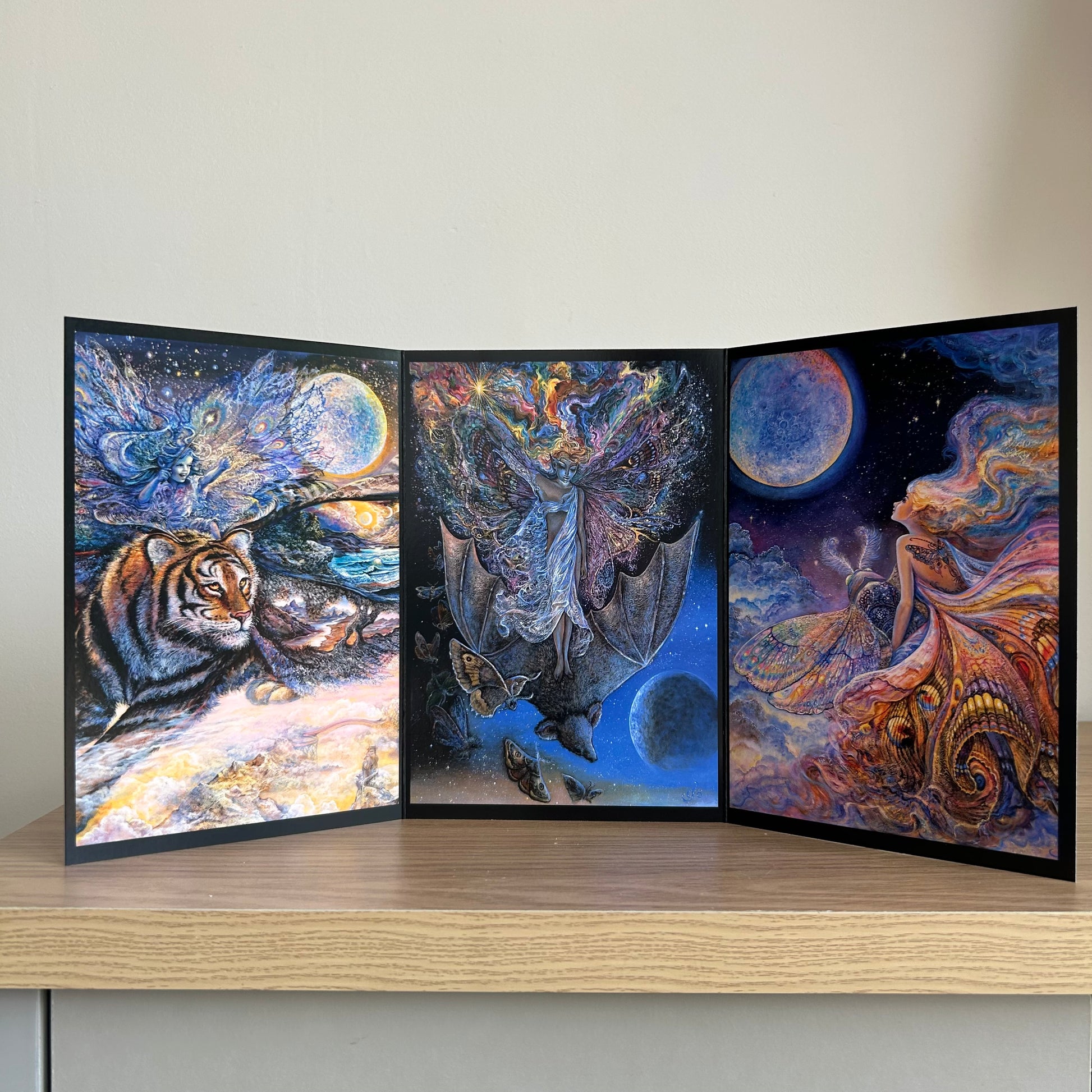 Three-panel self-sealing greetings card UK with artistic designs of fairy figures riding animals to the moon on a wooden surface.
