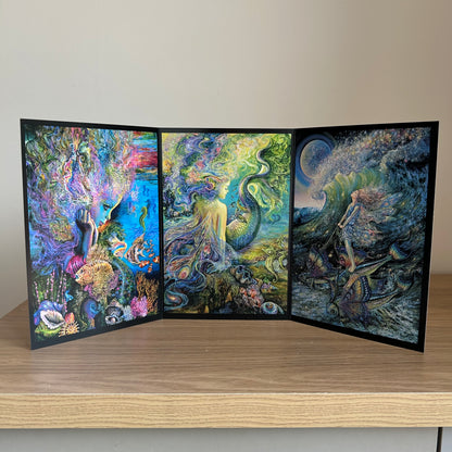 Three-panel self-sealing greetings card UK with artistic designs of under the sea and mermaid figures on a wooden surface.