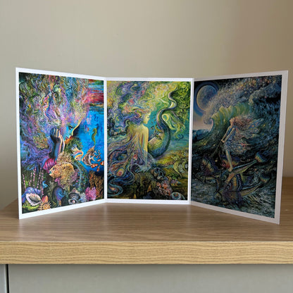 Three-panel self-sealing greetings card UK with artistic designs of under the sea and mermaid figures on a wooden surface.