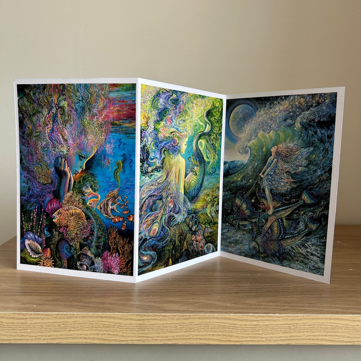 Self-sealing Greetings card with Triptych artwork of underwater scenes with mermaids and sea creatures on a wooden surface.