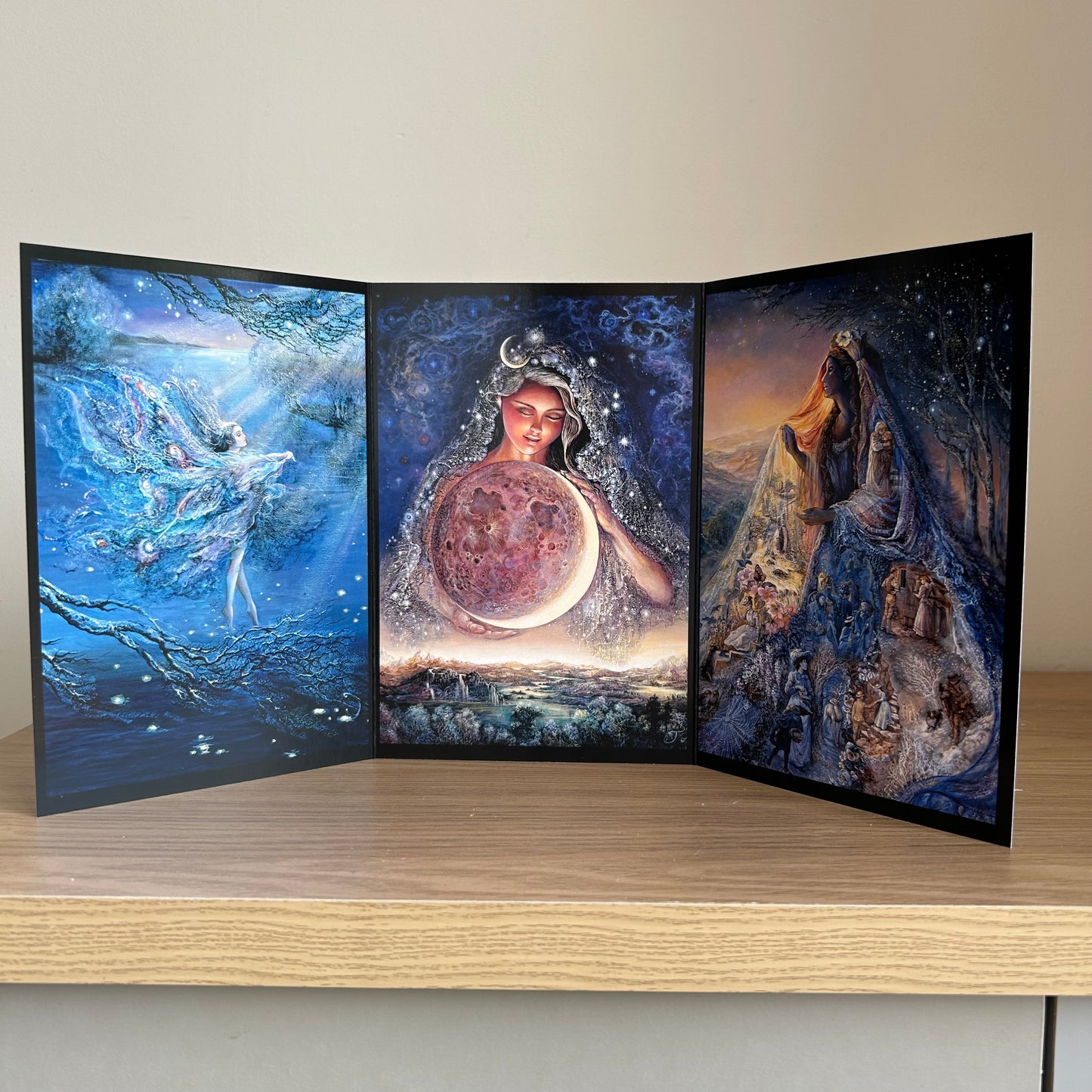Three-panel self-sealing greetings card UK with artistic fantasy designs featuring Josephine Wall paintings of the moon and mystical fairies and goddesses on a wooden surface