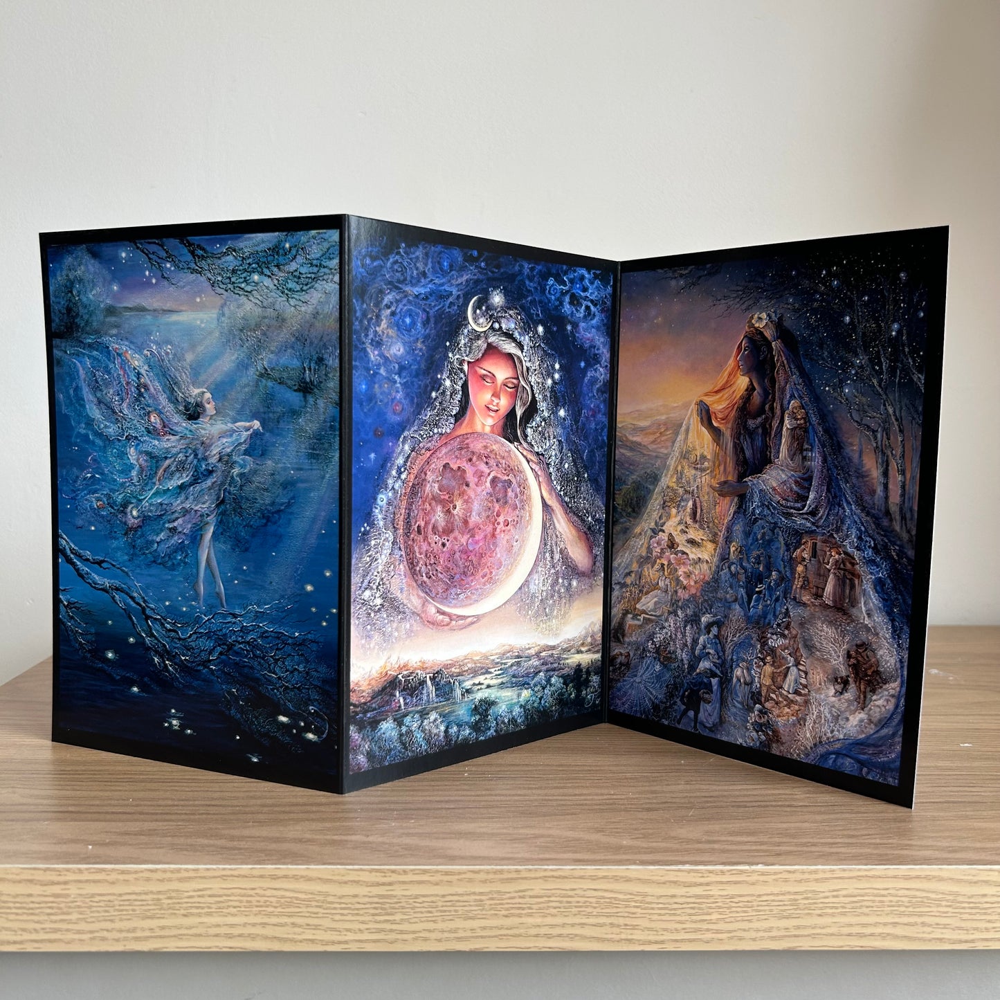Three-panel self-sealing greetings card UK with artistic fantasy designs featuring Josephine Wall paintings of the moon and mystical fairies and goddesses on a wooden surface