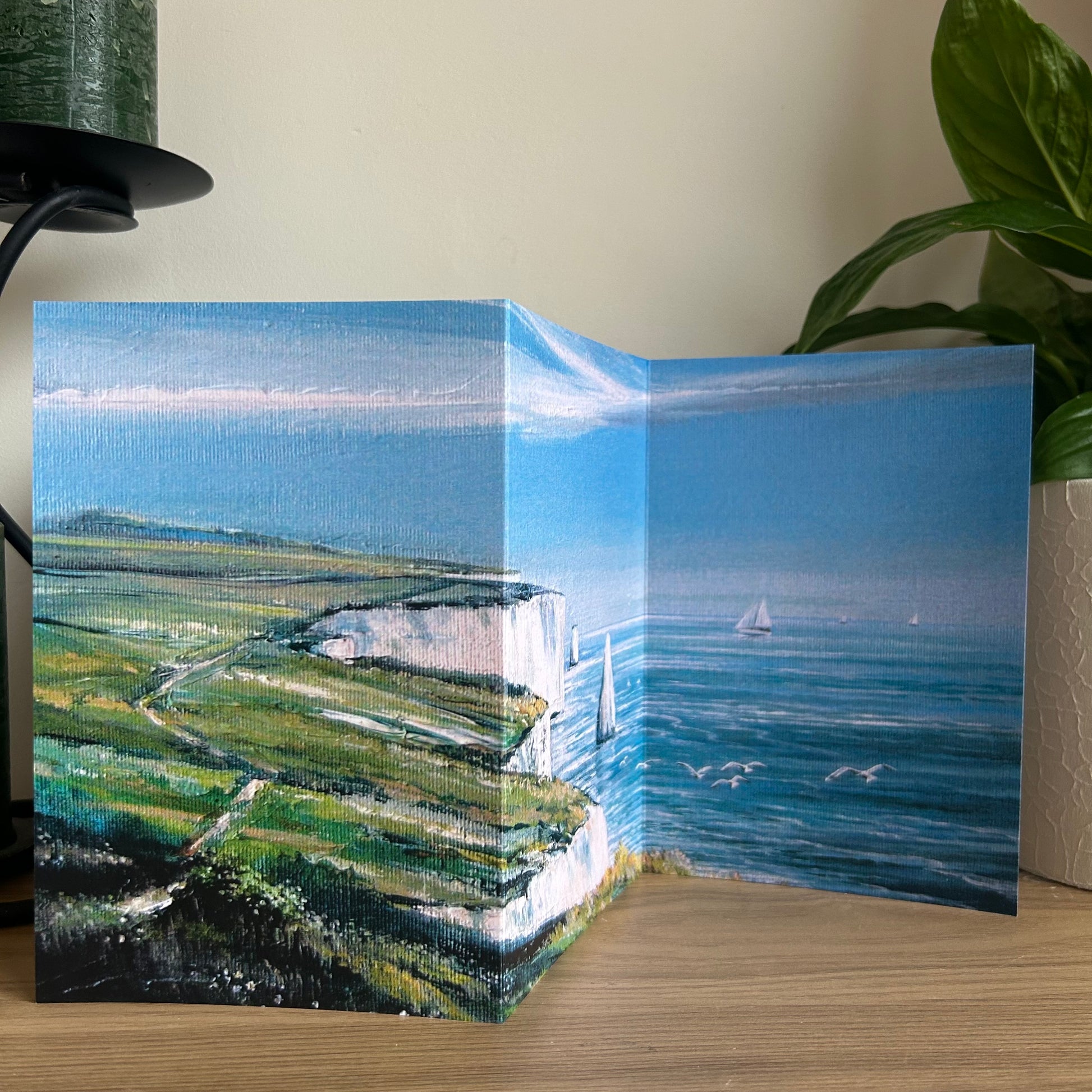 Greeting card with a scenic landscape of a coastal view on a wooden surface.