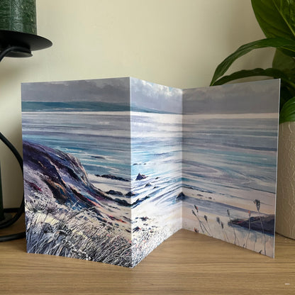 Greeting card with a scenic design of a coastal landscape on a wooden surface.