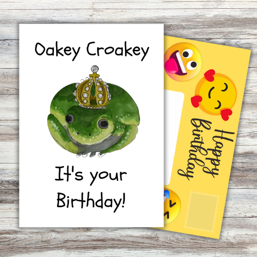 Image shows front of card which reads 'Oakey Croakey It's your birthday!' with a picture of a green toad wearing a crown. Yellow fully-illustrated Front posting page is sticking out behind card.