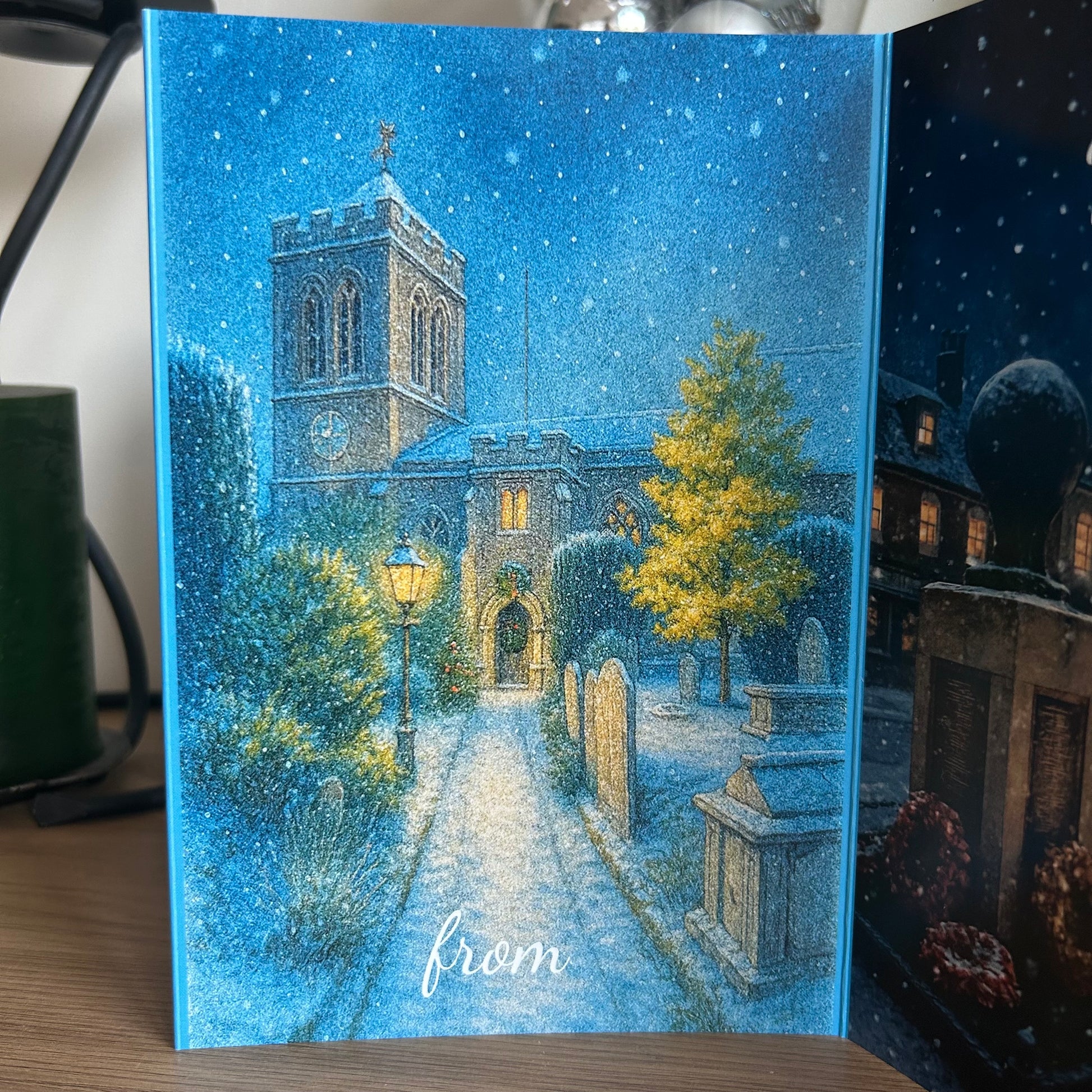 Greeting card with a snowy scene of a church and tombstones, featuring the word 'from'.