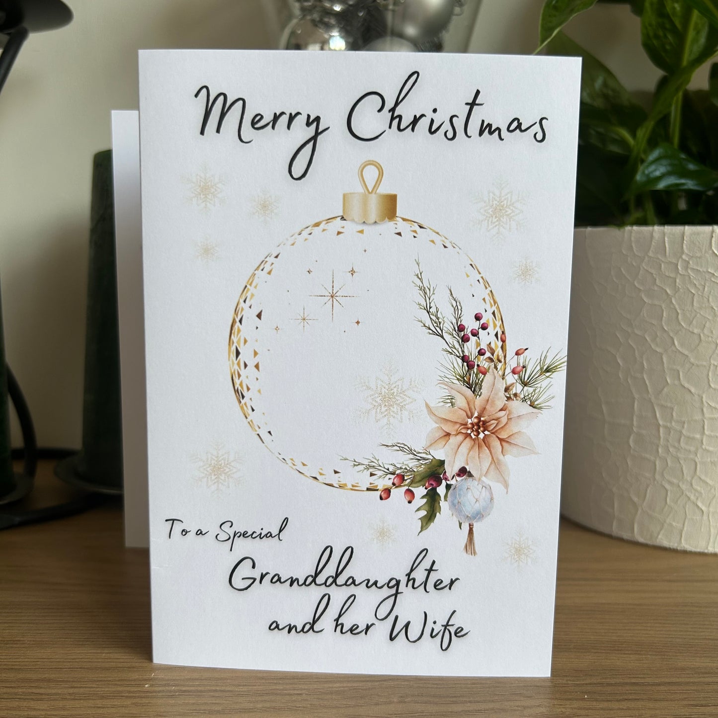 Christmas card with floral ornament design and personalized message on a wooden surface.