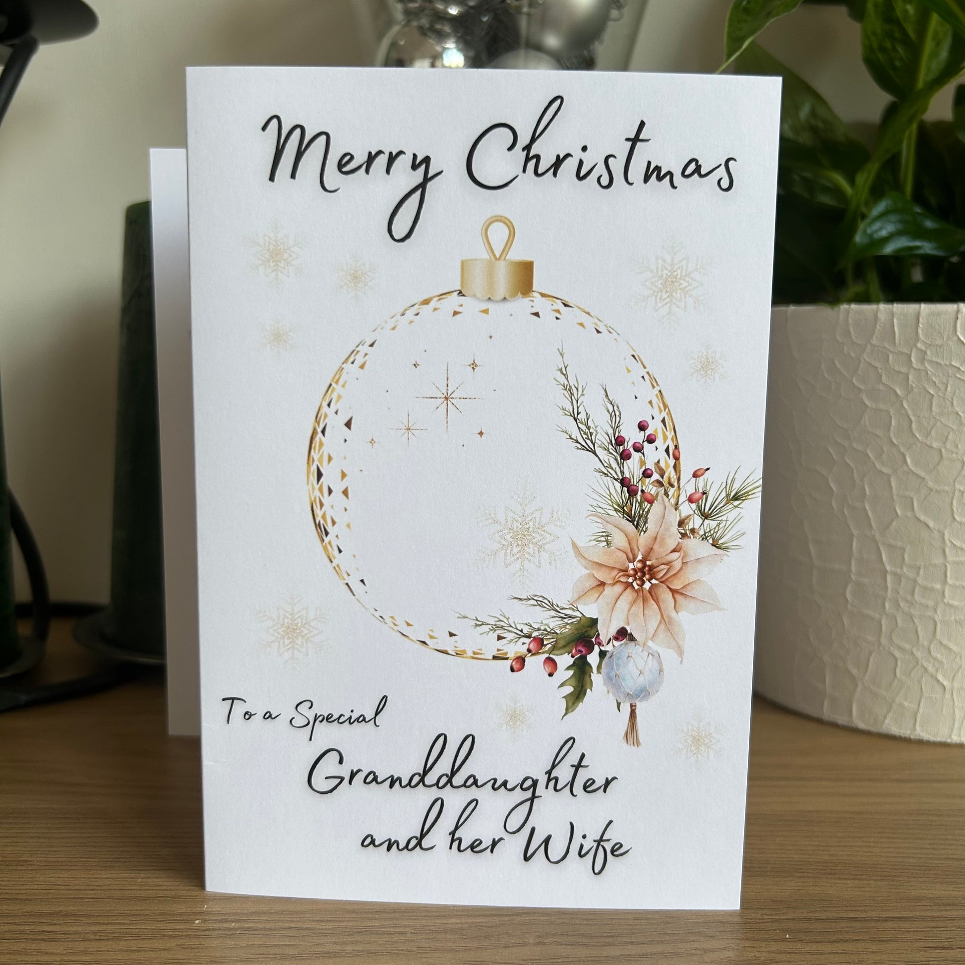 Christmas card with floral ornament design and personalized message on a wooden surface.