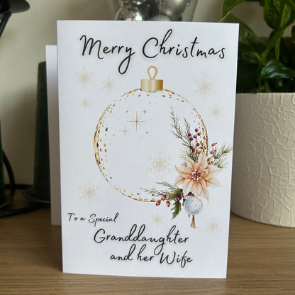Christmas card with floral ornament design and personalized message on a wooden surface.