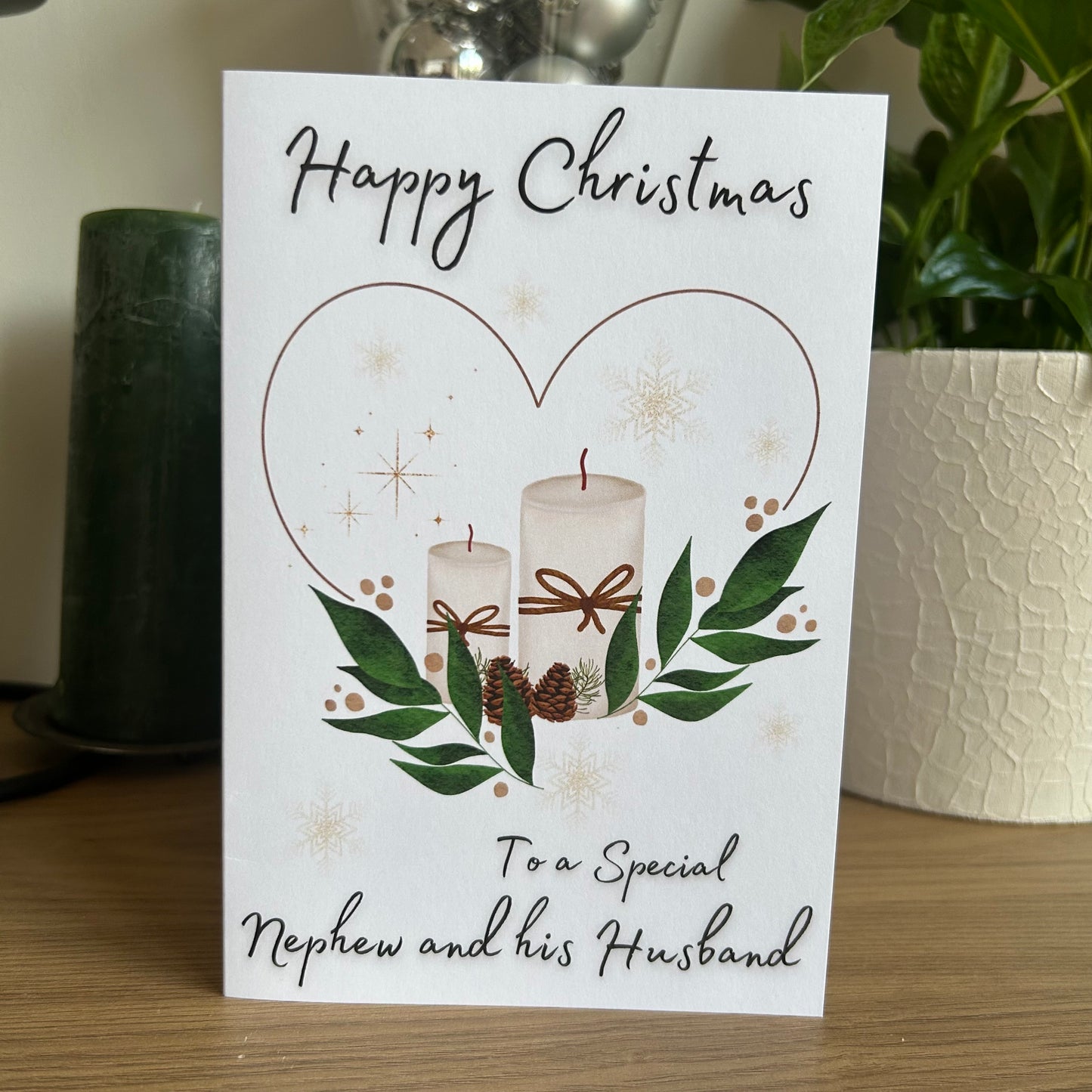 Christmas card with candles and greenery on a wooden surface