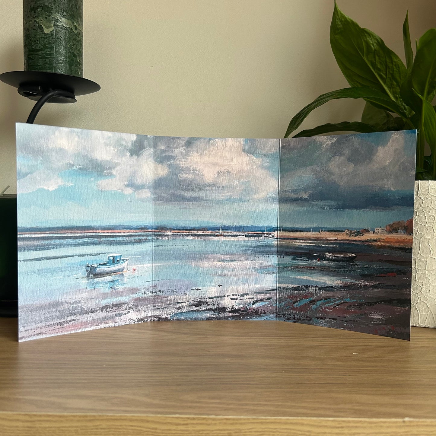 Foldable art greetings card of a coastal scene with boats on a wooden surface.