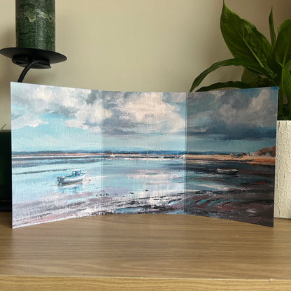 Foldable art greetings card of a coastal scene with boats on a wooden surface.
