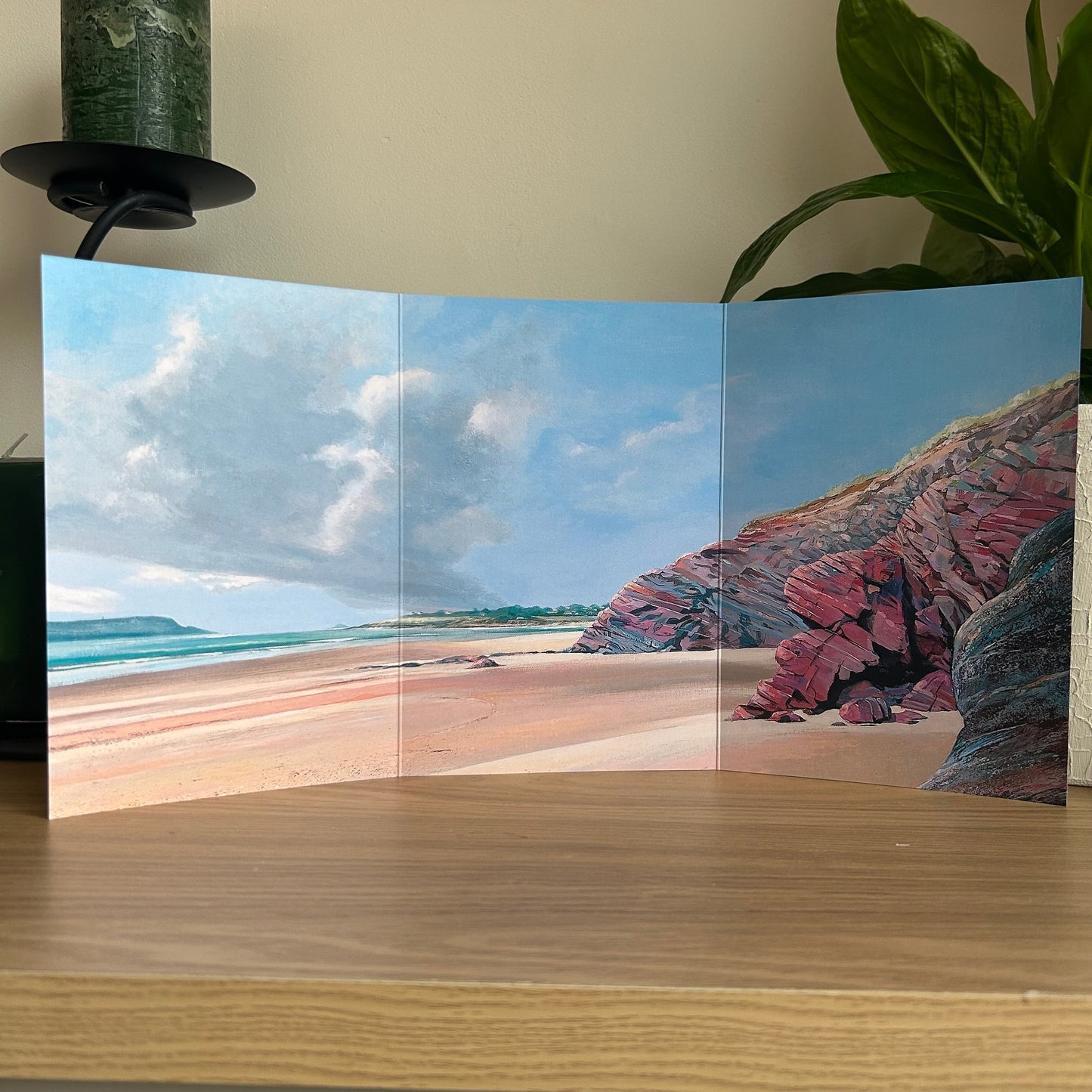 Trifold greetings card displaying a beach scene with a rocky outcrop on a wooden surface.