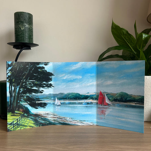 self-sealing greetings card showing a trifold painting of a scenic landscape with sailboats on the Fal on a wooden surface.