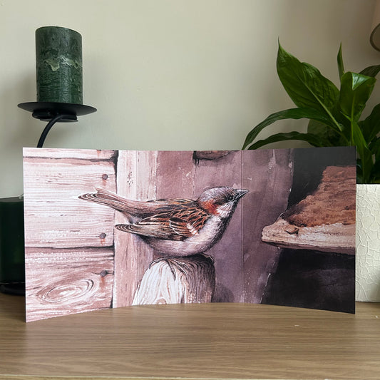 Trifold Greetings Card with a sparrow design on a wooden surface with a plant and candle in the background