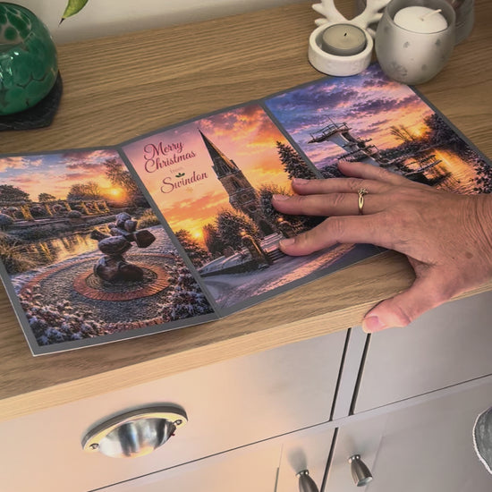 Demonstration of the Bare Cards Christmas Card for Swindon, showing how to write, fold seal, open and display the self-sealing card. This triptych card shows  festive images of Queen's Park, Christchurch and Coate Water at dusk.