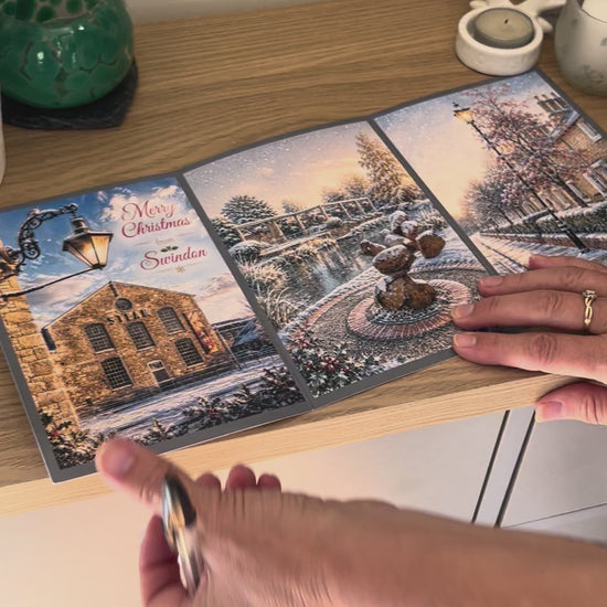 Demonstration of the Bare Cards Christmas Card for Swindon, showing how to write, fold seal, open and display the self-sealing card. This triptych card shows  festive images of Steam Museum, Queen's Park, Christchurch and The Railway Village