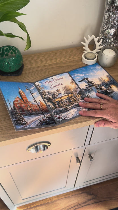 Demonstration of the Bare Cards Christmas Card for Swindon, showing how to write, fold seal, open and display the self-sealing card. This triptych card shows  festive images of The Town Hall, the pavillion in Old Town Gardens and the diving board Coate Water.