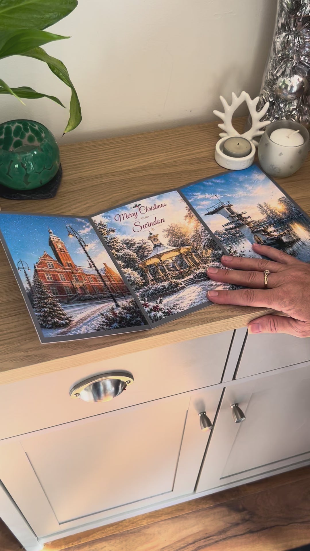 Demonstration of the Bare Cards Christmas Card for Swindon, showing how to write, fold seal, open and display the self-sealing card. This triptych card shows  festive images of The Town Hall, the pavillion in Old Town Gardens and the diving board Coate Water.